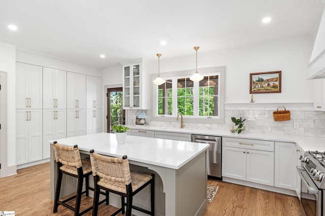 kitchen featuring a sink, a breakfast bar area, stainless steel appliances, backsplash, and white cabinetry
