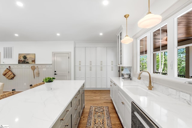 kitchen featuring light stone counters, a sink, light wood-type flooring, gray cabinetry, and visible vents