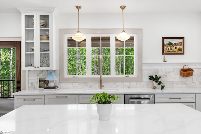 kitchen featuring glass insert cabinets, dishwasher, a sink, and tasteful backsplash