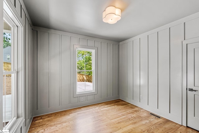 unfurnished room with a decorative wall, visible vents, and light wood-style flooring