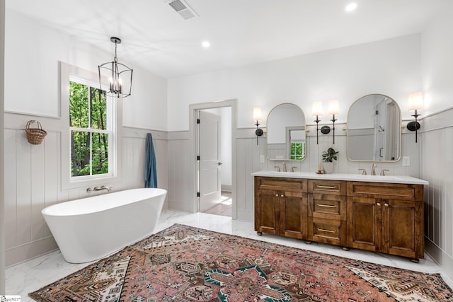 bathroom featuring a sink, a freestanding bath, wainscoting, visible vents, and marble finish floor