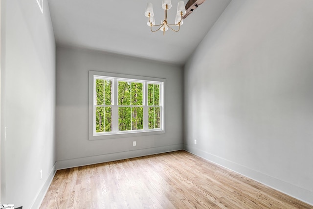 unfurnished room featuring lofted ceiling, baseboards, wood finished floors, and an inviting chandelier