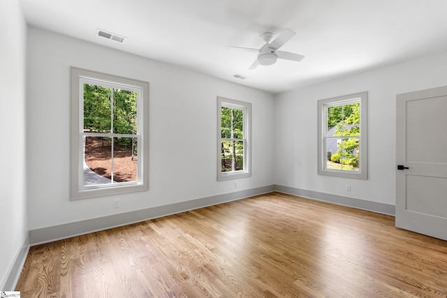 empty room featuring light wood finished floors, visible vents, and plenty of natural light