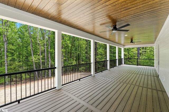 deck featuring ceiling fan and a forest view