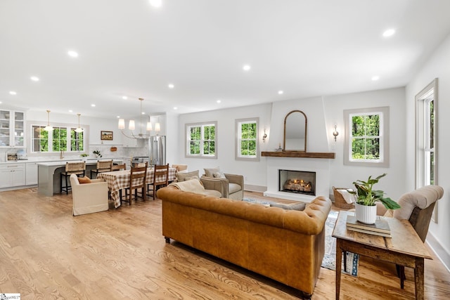 living area with recessed lighting, light wood-style floors, a healthy amount of sunlight, and a lit fireplace
