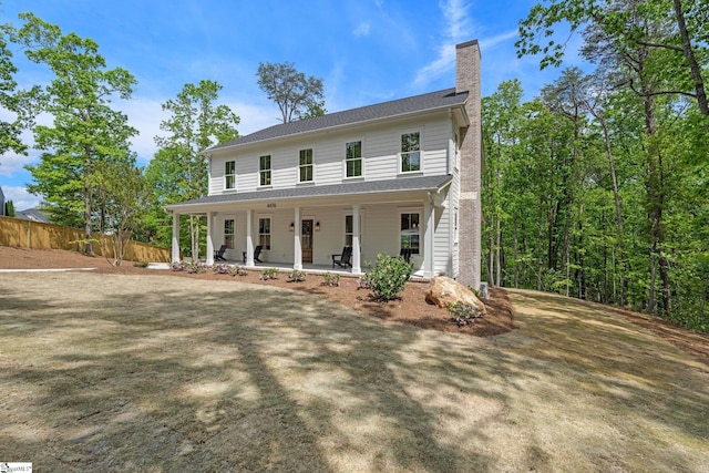 view of front of house with a chimney, fence, and covered porch