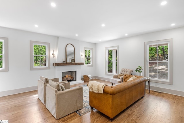 living room with recessed lighting, a warm lit fireplace, and baseboards