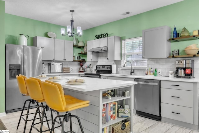 kitchen featuring decorative backsplash, appliances with stainless steel finishes, open shelves, and a sink