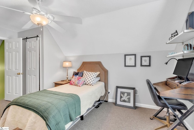 carpeted bedroom with a barn door, lofted ceiling, baseboards, and ceiling fan