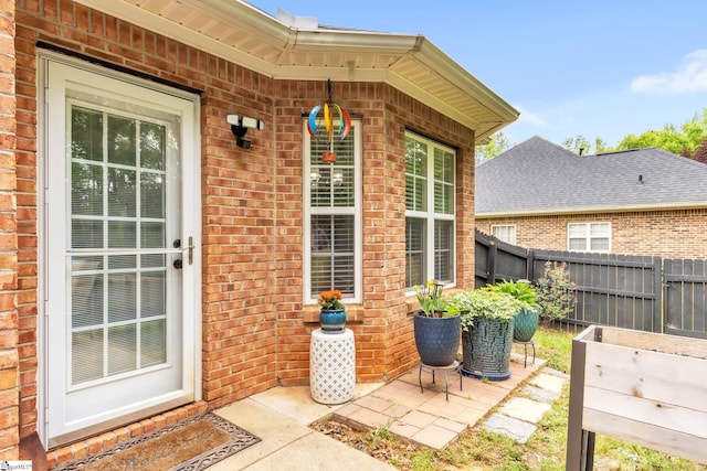 entrance to property with fence, brick siding, and a patio