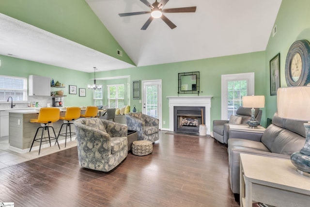 living area with a fireplace with flush hearth, wood finished floors, visible vents, and ceiling fan with notable chandelier