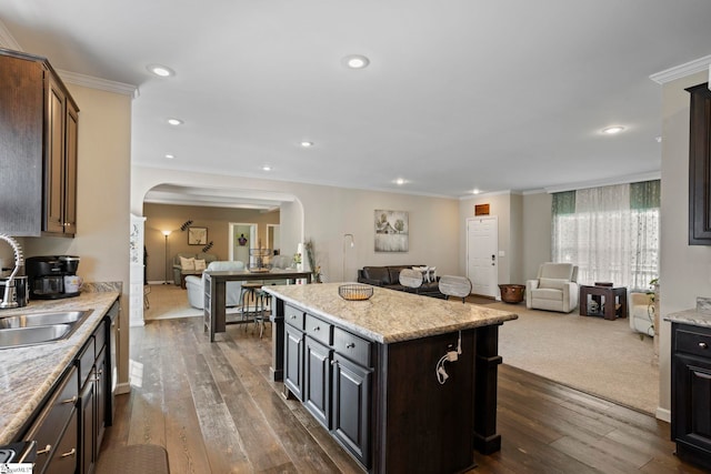 kitchen featuring open floor plan, a center island, a sink, and arched walkways