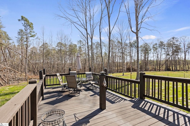 deck with outdoor dining area and a yard