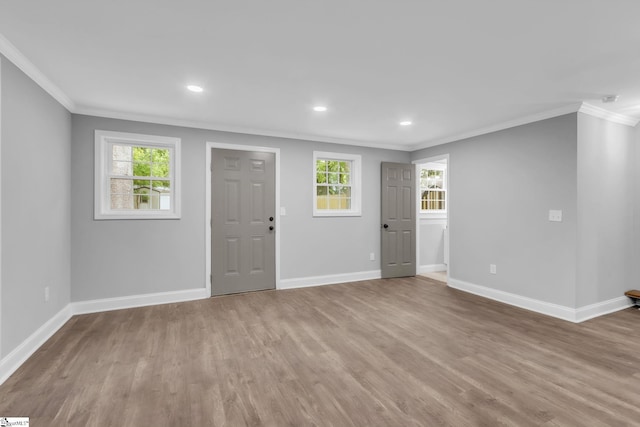 foyer entrance with baseboards, wood finished floors, ornamental molding, and a healthy amount of sunlight