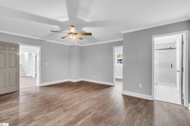 unfurnished bedroom with wood finished floors, ornamental molding, baseboards, ceiling fan, and ensuite bathroom