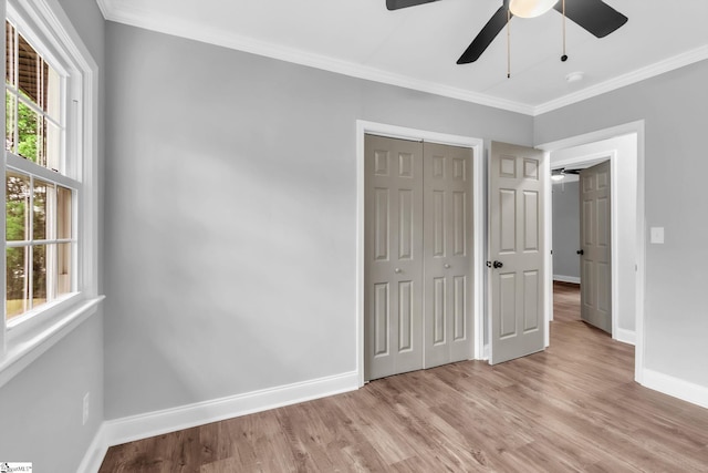 unfurnished bedroom featuring light wood finished floors, baseboards, ornamental molding, and multiple windows