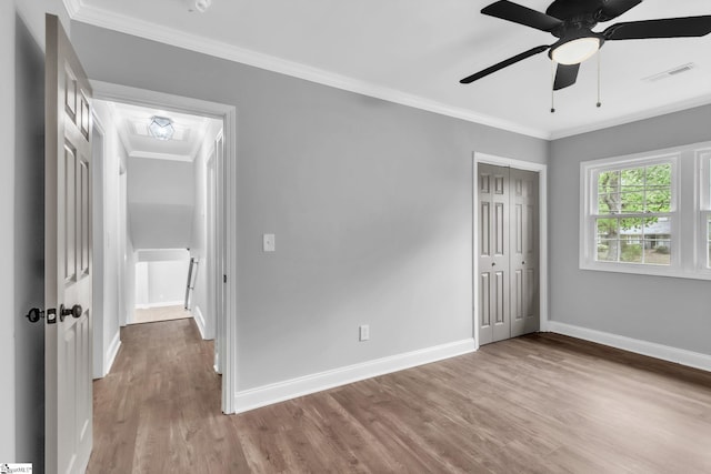 unfurnished bedroom with visible vents, baseboards, wood finished floors, a closet, and crown molding