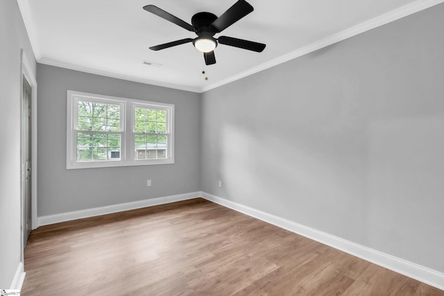 spare room with visible vents, baseboards, a ceiling fan, wood finished floors, and crown molding