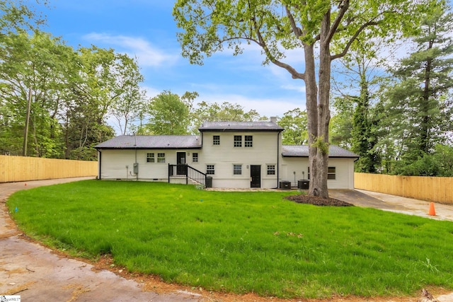rear view of house with a chimney, fence, central air condition unit, and a yard
