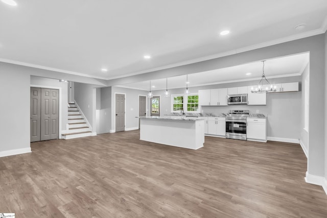 kitchen with baseboards, white cabinetry, appliances with stainless steel finishes, a kitchen island, and ornamental molding