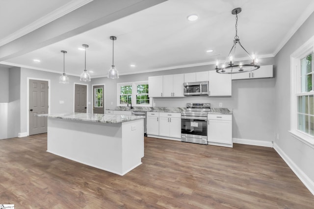 kitchen featuring white cabinetry, ornamental molding, stainless steel appliances, and an inviting chandelier
