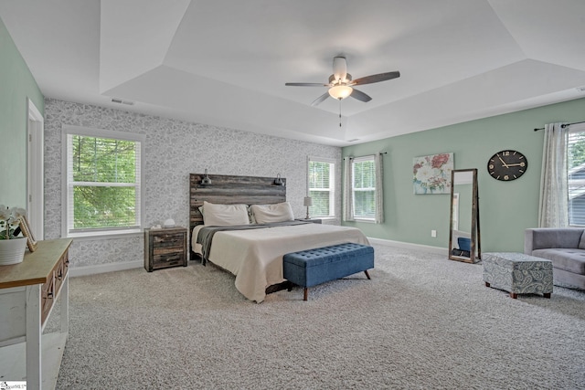 carpeted bedroom with baseboards, a ceiling fan, and a raised ceiling