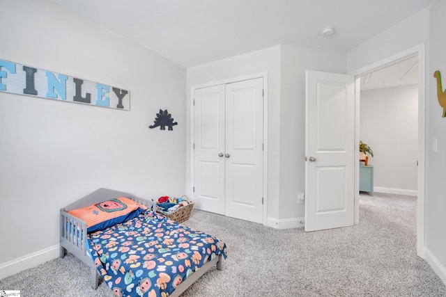 carpeted bedroom featuring a closet and baseboards