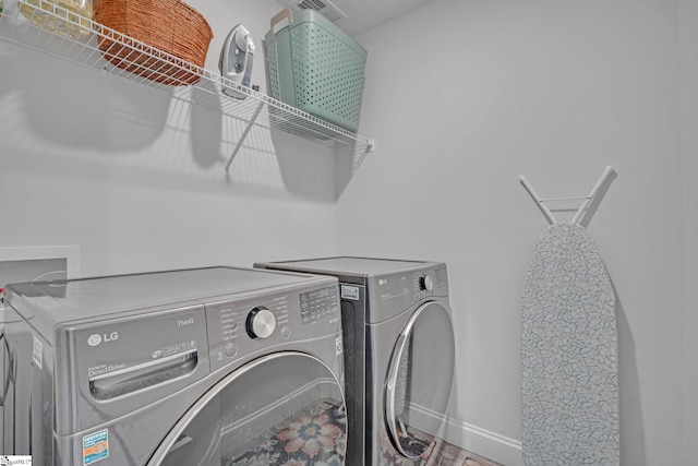 washroom with baseboards, washer and dryer, and laundry area