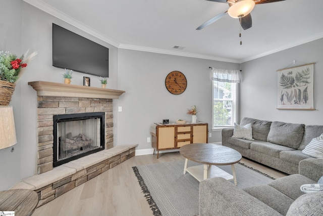 living area with visible vents, wood finished floors, ceiling fan, a fireplace, and ornamental molding