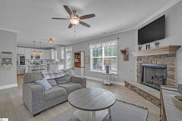 living area with baseboards, crown molding, and light wood-style floors