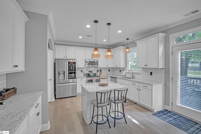 kitchen featuring a sink, light wood-type flooring, visible vents, backsplash, and appliances with stainless steel finishes