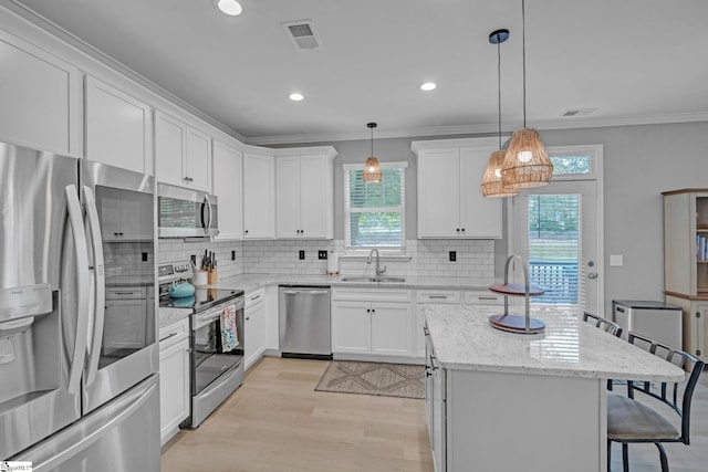kitchen with light wood finished floors, stainless steel appliances, backsplash, a sink, and a breakfast bar area