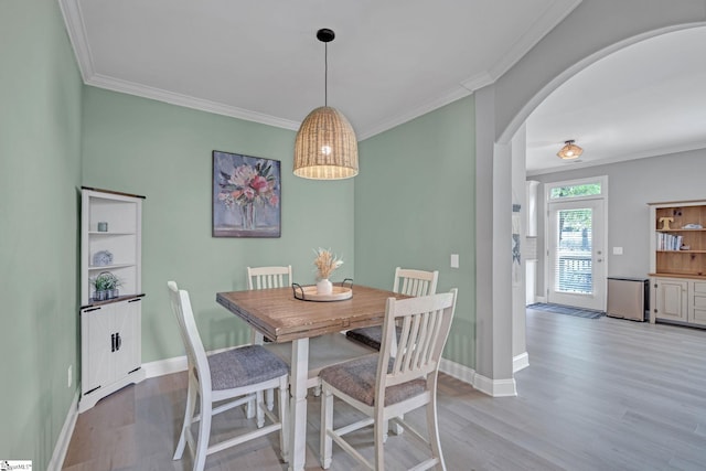 dining space with arched walkways, crown molding, wood finished floors, and baseboards