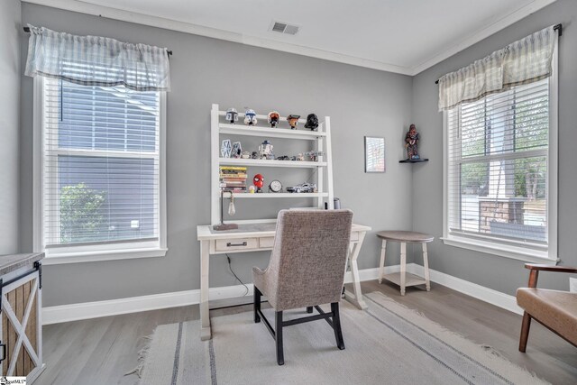 home office with light wood-type flooring, visible vents, crown molding, and baseboards