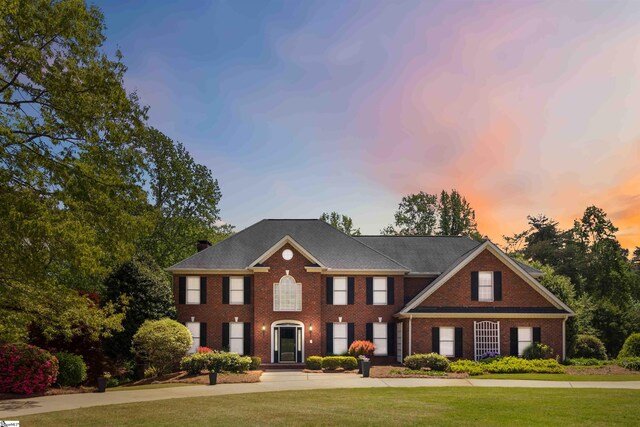 view of front of home with a chimney, brick siding, and a front yard