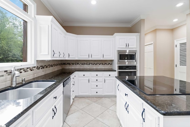 kitchen with dark stone counters, a sink, white cabinets, backsplash, and appliances with stainless steel finishes