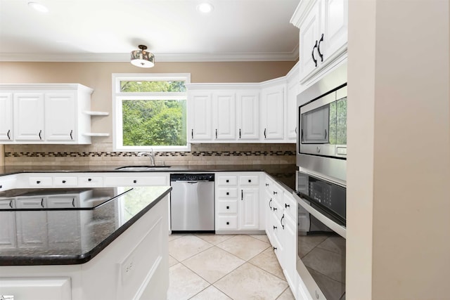 kitchen with white cabinets, stainless steel appliances, light tile patterned floors, a sink, and decorative backsplash