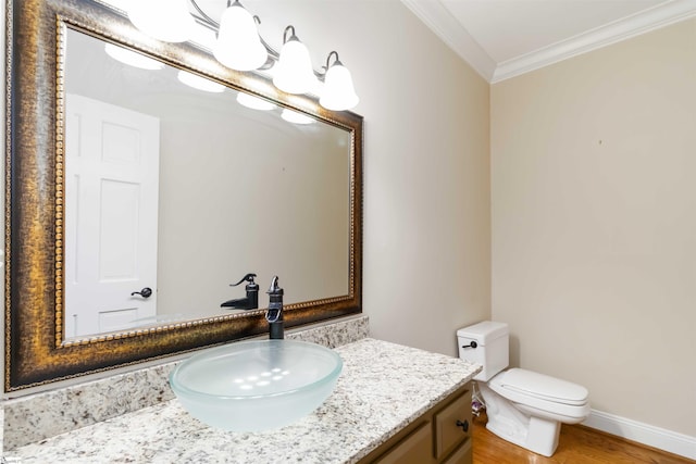 bathroom with wood finished floors, toilet, vanity, crown molding, and baseboards