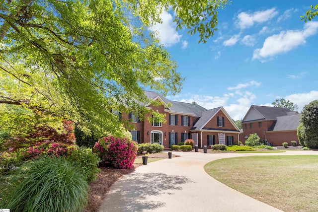 colonial inspired home featuring brick siding and a front lawn