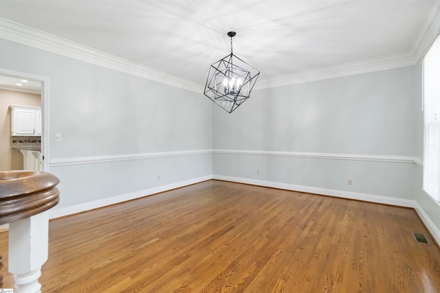 unfurnished dining area featuring an inviting chandelier, ornamental molding, wood finished floors, and visible vents