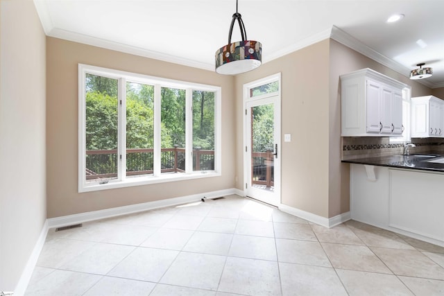 unfurnished dining area featuring a sink, light tile patterned flooring, baseboards, ornamental molding, and visible vents