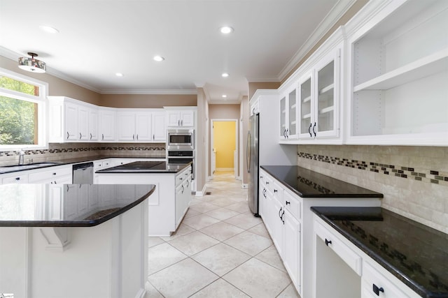 kitchen with tasteful backsplash, a sink, white cabinets, appliances with stainless steel finishes, and a kitchen island