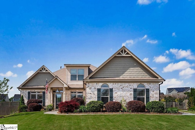 craftsman house featuring fence, a front lawn, and brick siding