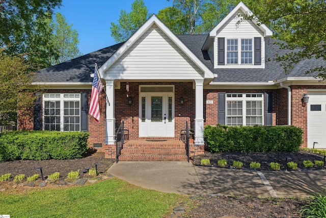 view of front facade with an attached garage, a shingled roof, and brick siding