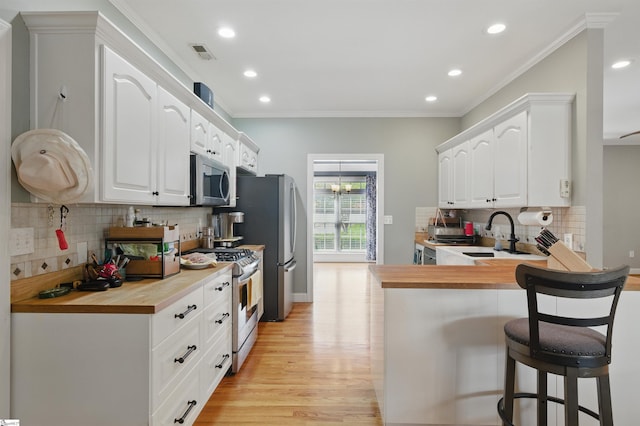 kitchen featuring a sink, backsplash, appliances with stainless steel finishes, a breakfast bar, and ornamental molding