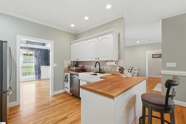 kitchen featuring a kitchen breakfast bar, a sink, tasteful backsplash, appliances with stainless steel finishes, and white cabinetry