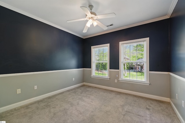 carpeted spare room with ceiling fan, baseboards, crown molding, and visible vents
