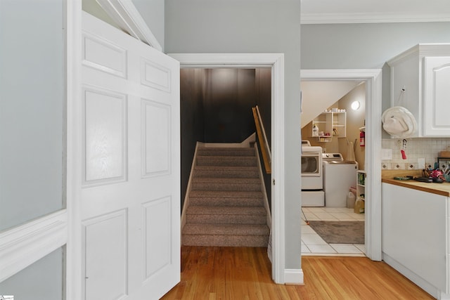 stairway with separate washer and dryer, wood finished floors, and ornamental molding