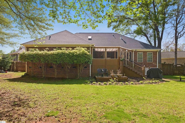 rear view of property featuring fence, a sunroom, and a yard