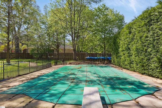 view of swimming pool featuring fence, a yard, a fenced in pool, and a diving board